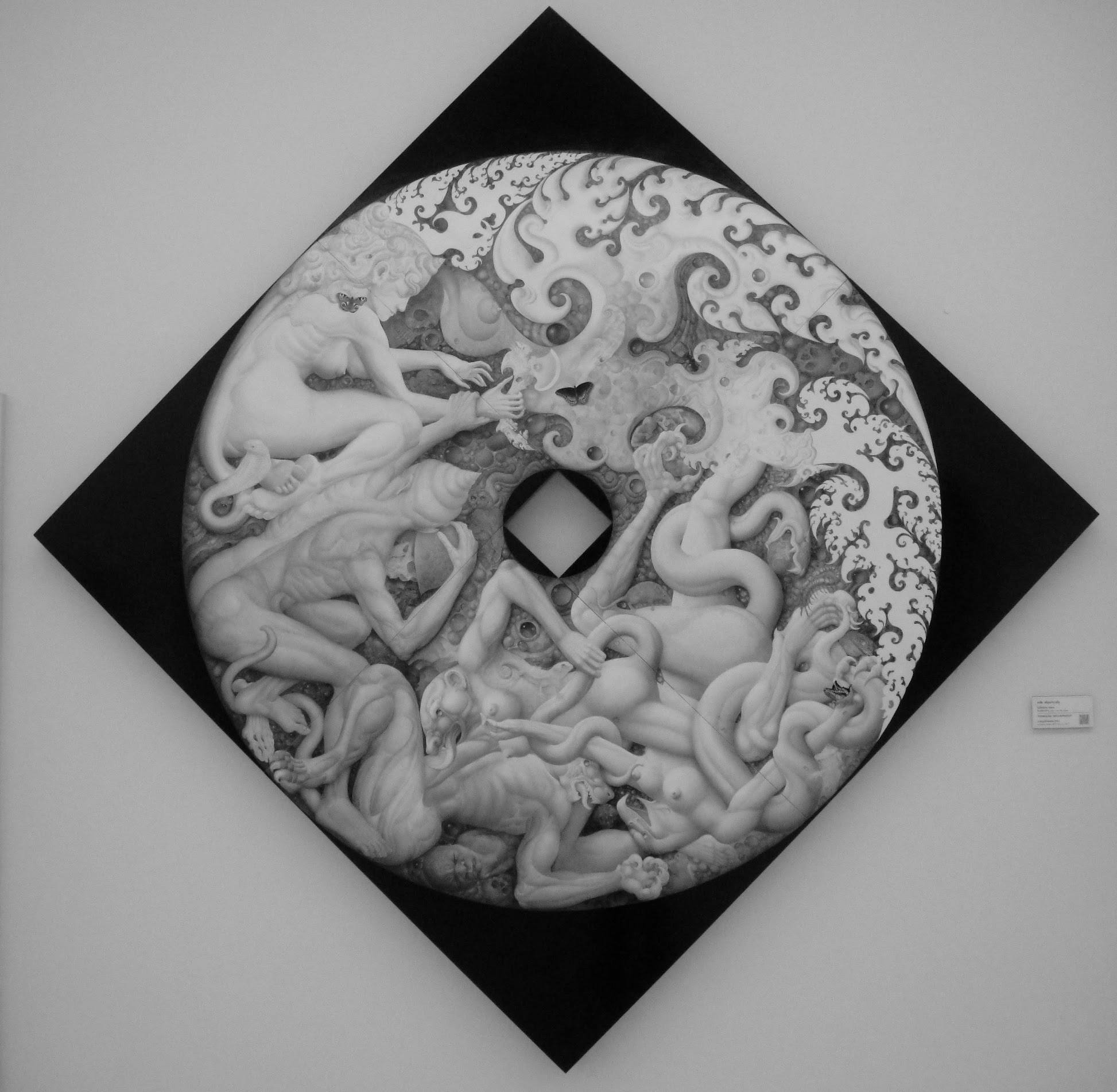 Black-and-white photograph of a circular painting filled with intertwined figures and swirling patterns, mounted on a dark diamond-shaped background.